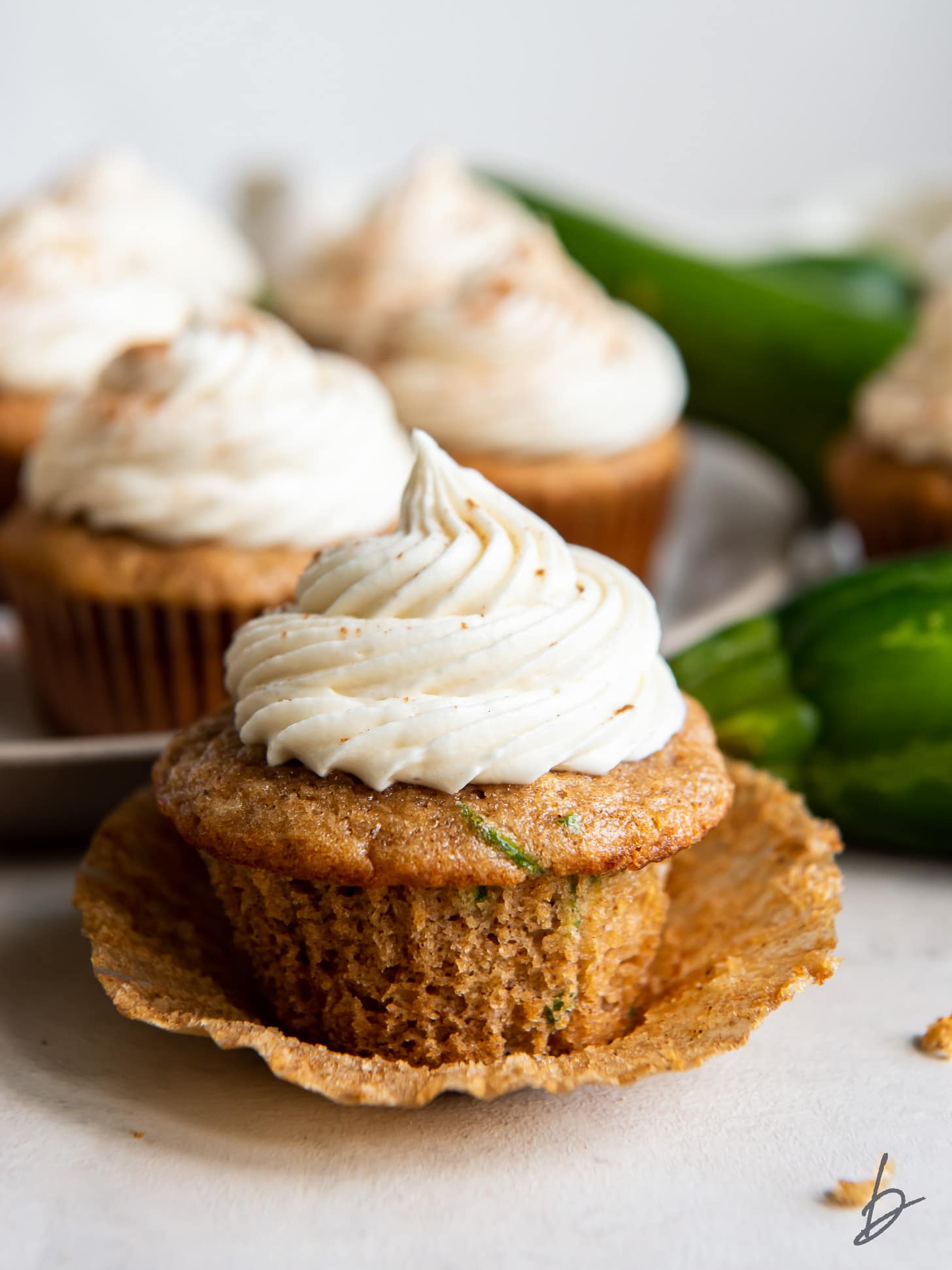 open cupcake liner with a zucchini cupcake with cream cheese frosting.