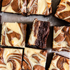 cream cheese swirl brownie on its side next to more brownies.