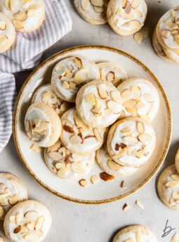 plate of almond sugar cookies with icing and sliced almonds for garnish.