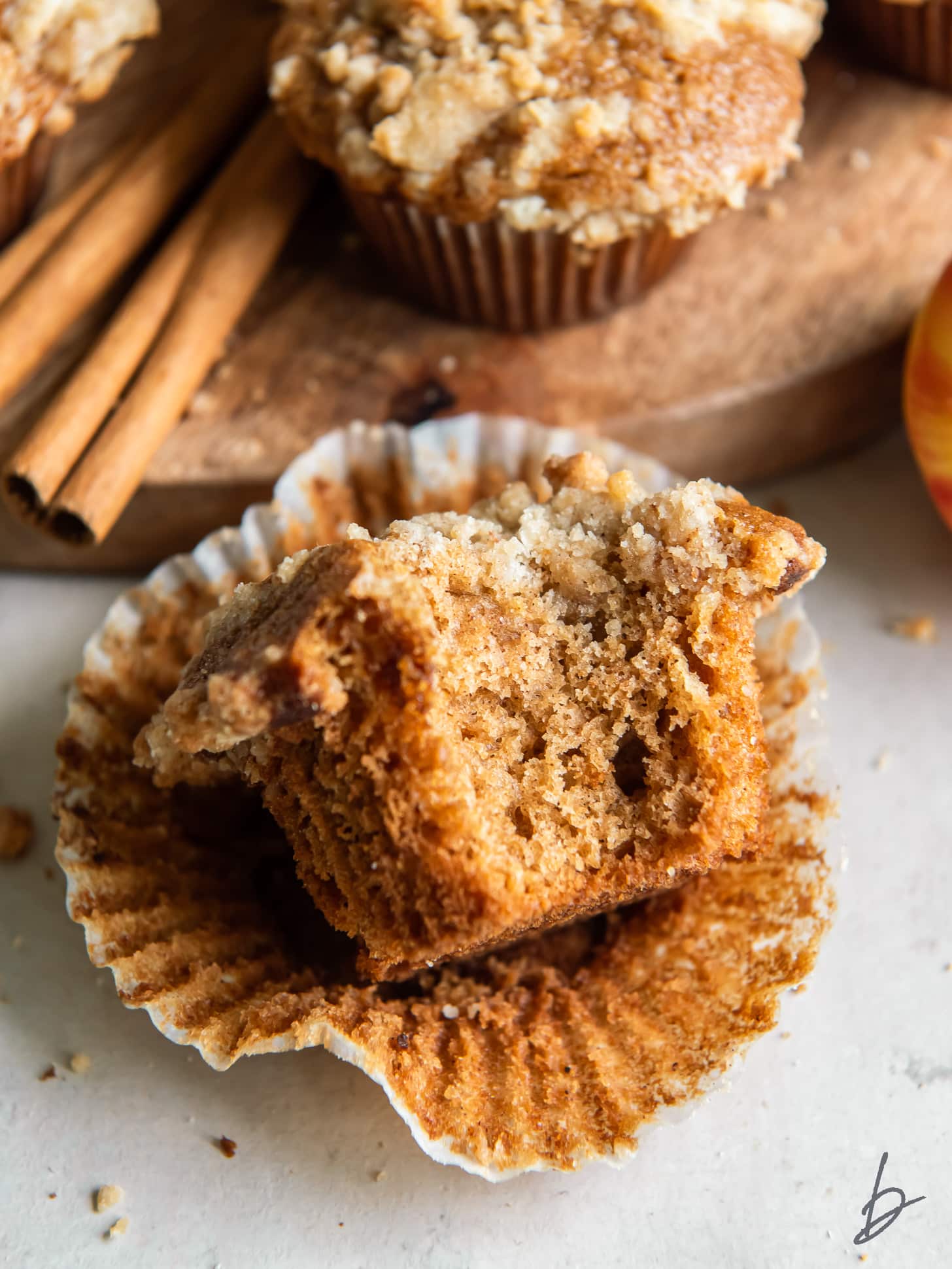 apple cider muffin with a bite sitting on open paper liner.