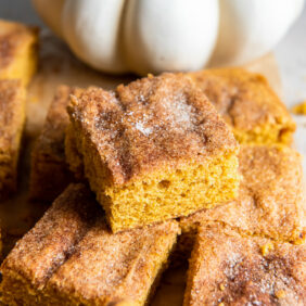 pumpkin snickerdoodle bar on top of more bars by white pumpkin.