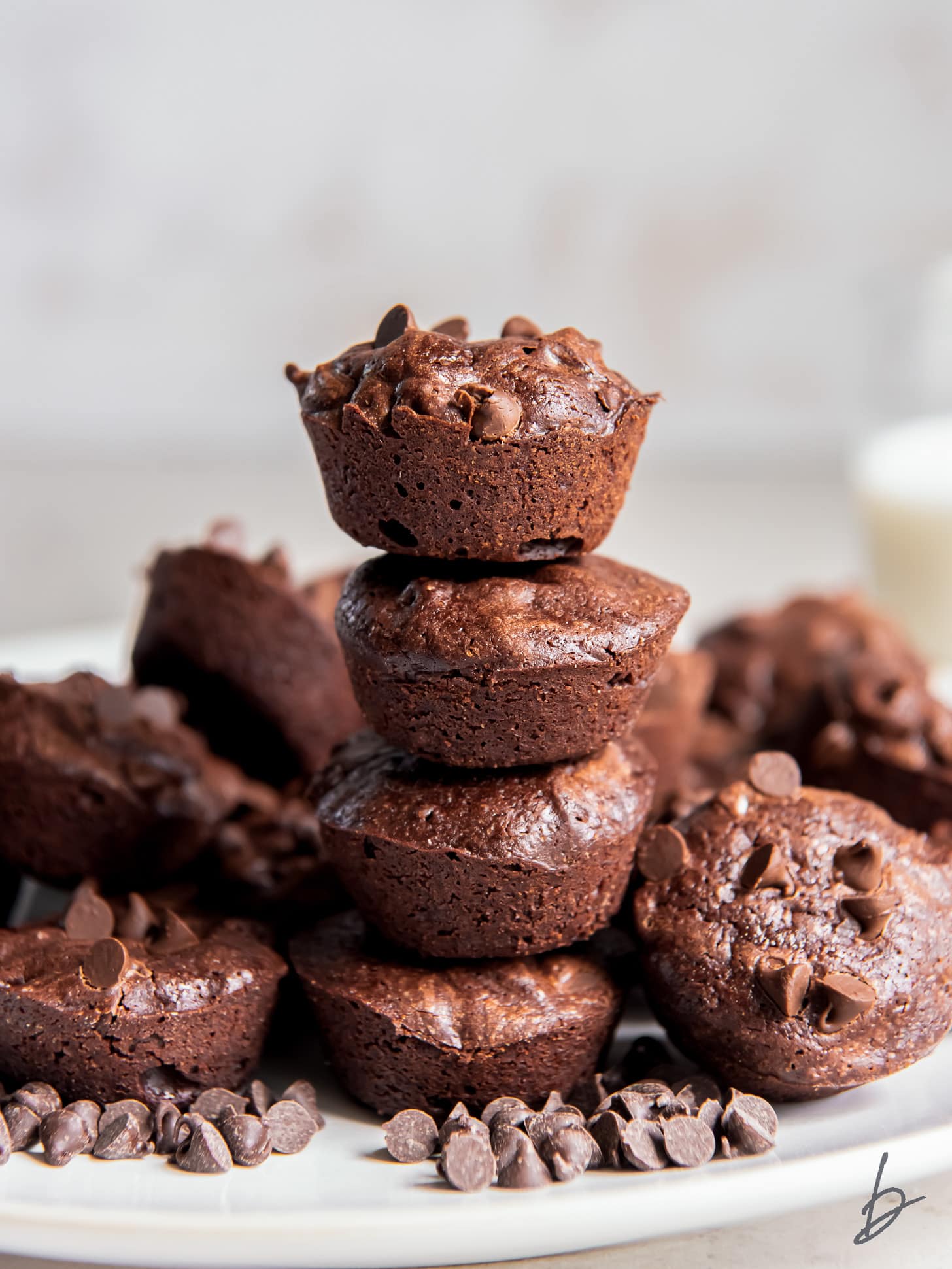 stack of four brownie bites on a plate with more  mini brownies.