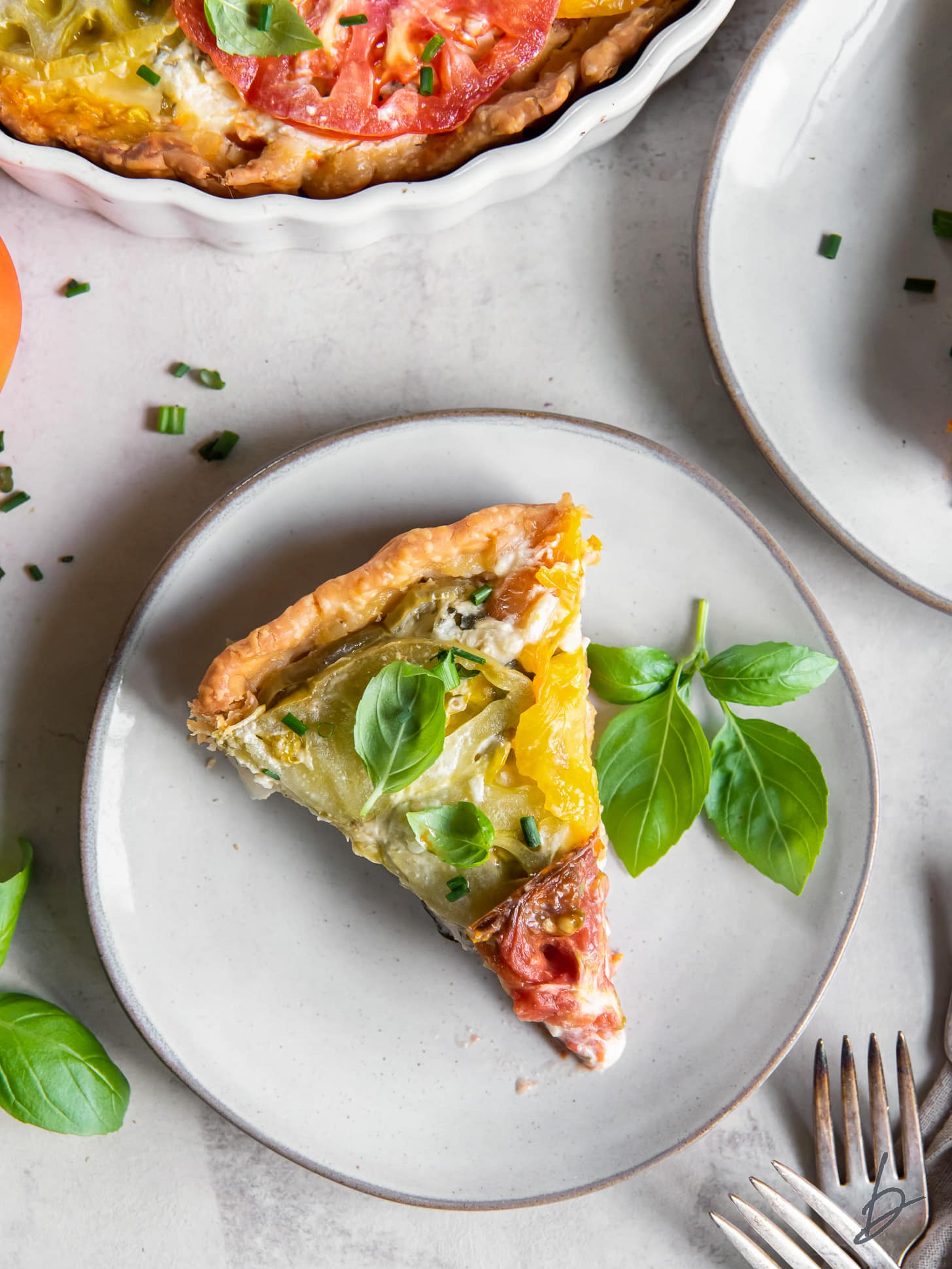 slice of tomato pie and sprig of basil on plate.