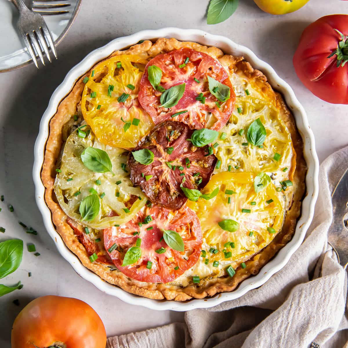 tomato pie with heirloom tomato slices on top and basil garnish.