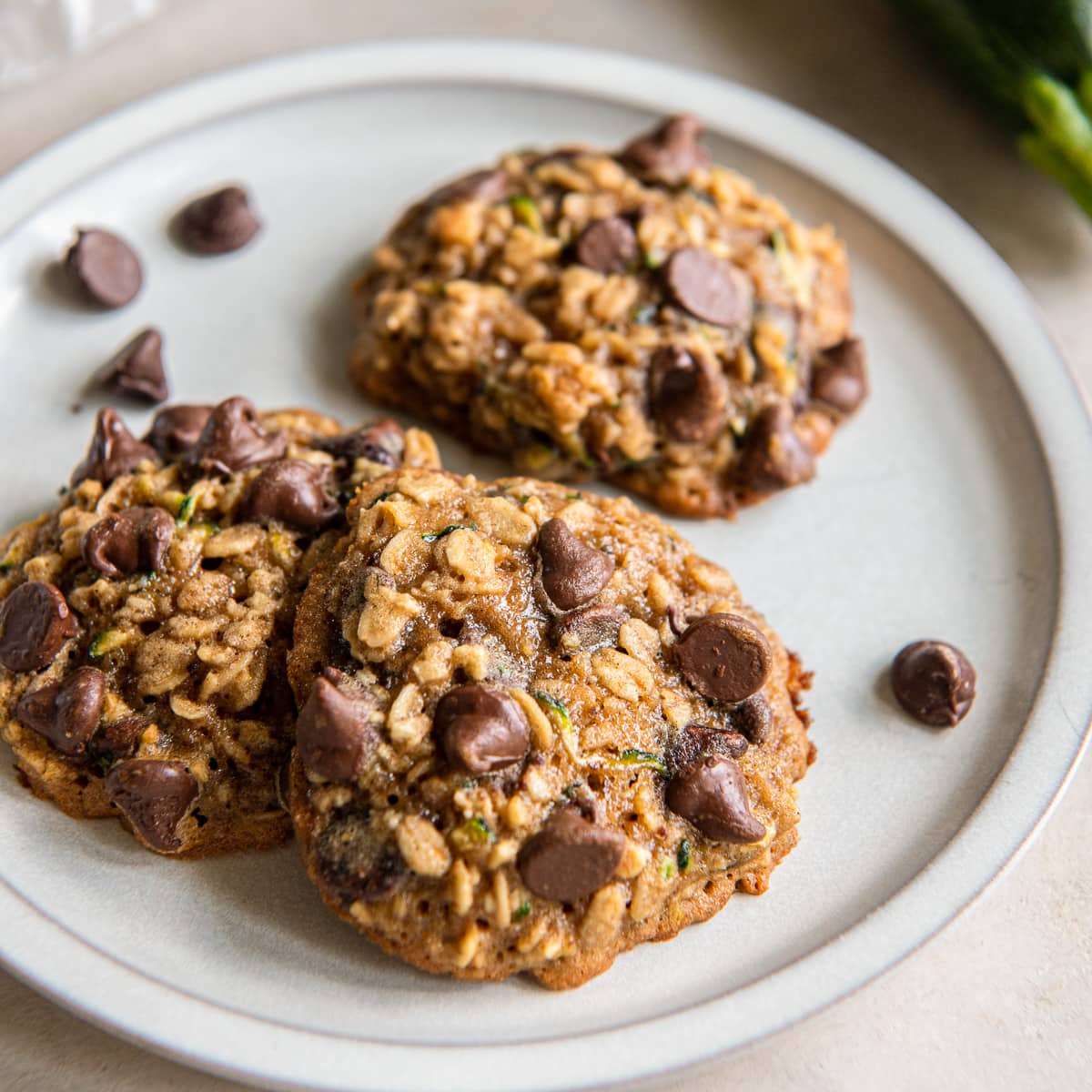three zucchini cookies on a plate with chocolate chips.