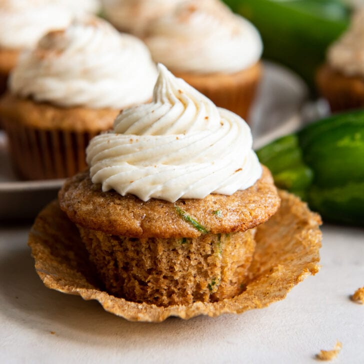 zucchini cupcakes with cream cheese frosting on an open paper liner.