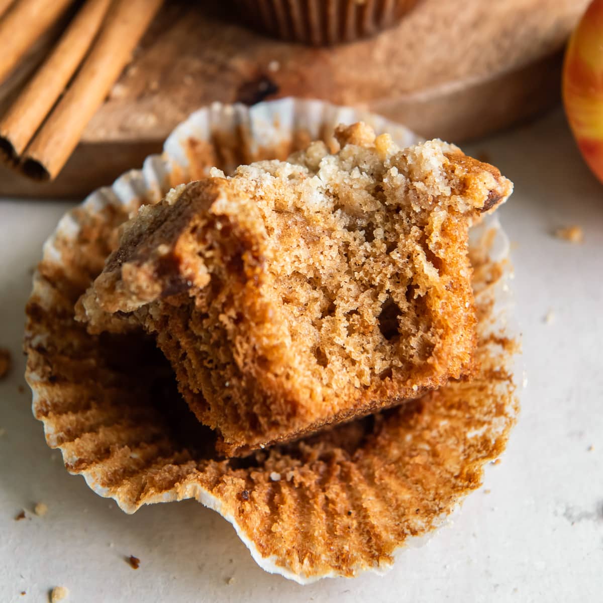 apple cider muffin with a bite on an open paper muffin liner.