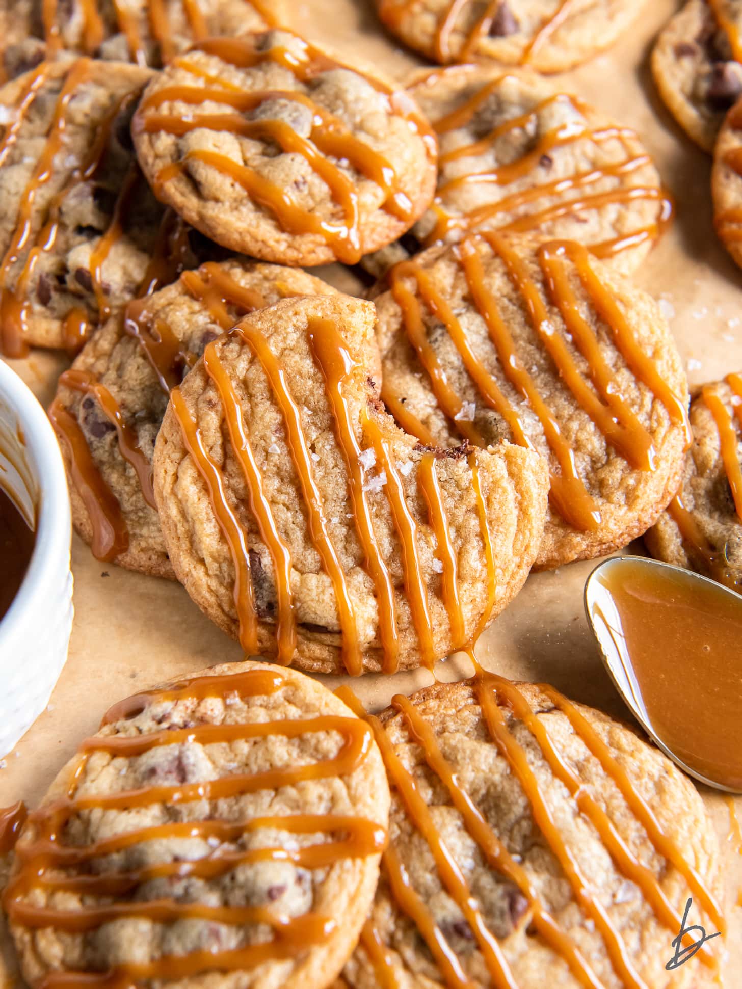 caramel cookie with bite leaning on other cookies with caramel drizzle.