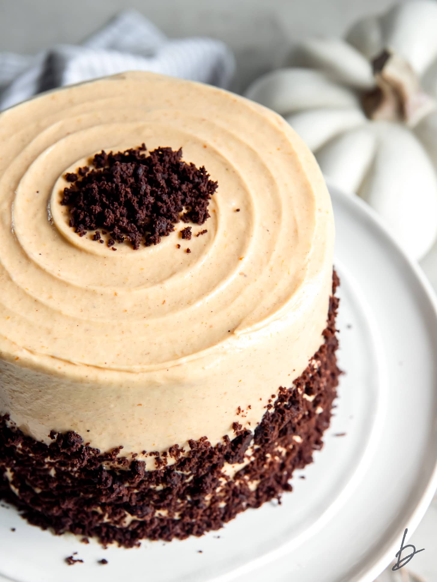 chocolate pumpkin cake with pumpkin cream cheese frosting on a cake plate.