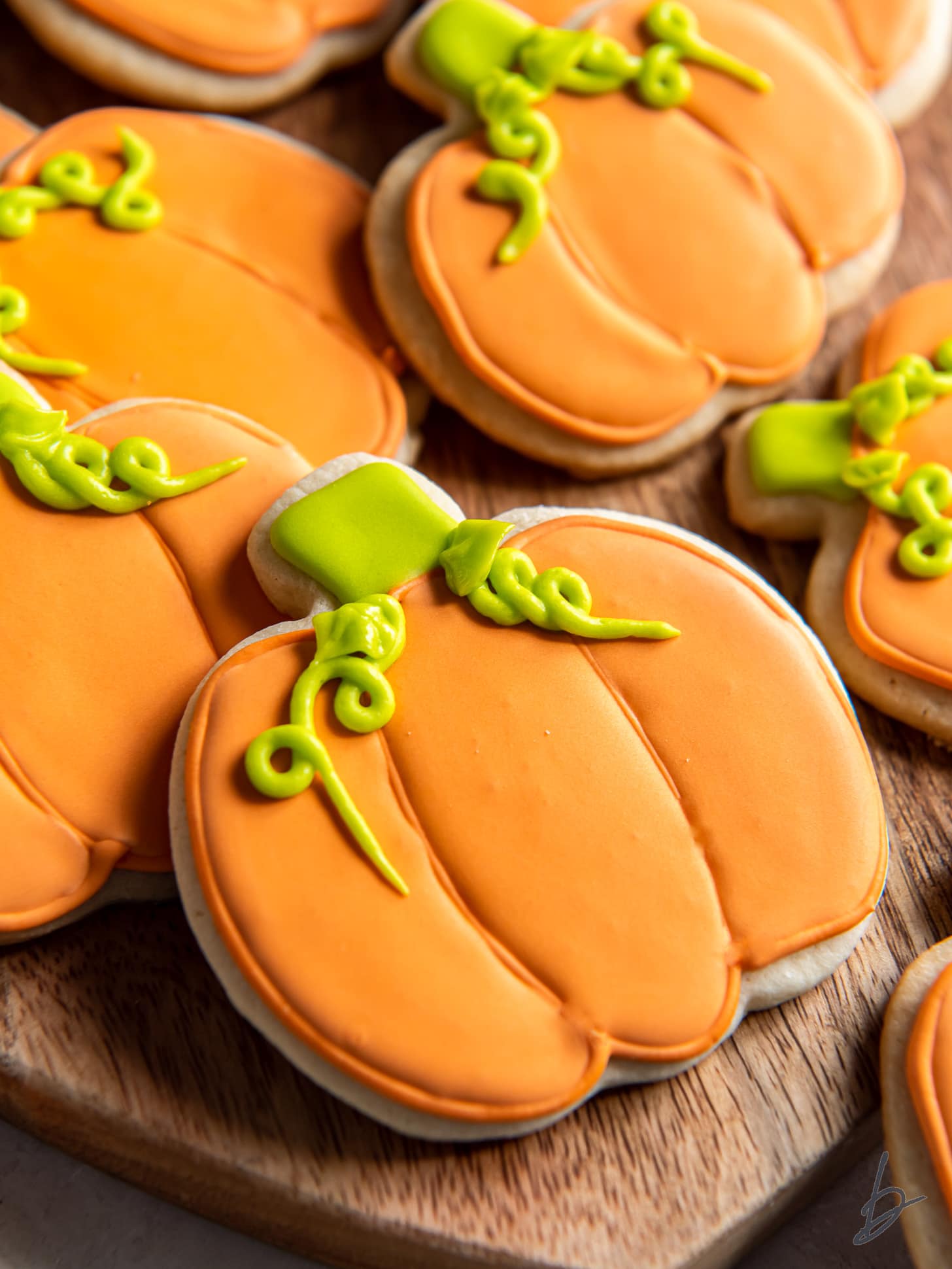 pumpkin sugar cookie with orange and green royal icing decoration.