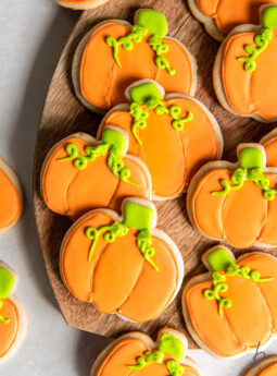 decorated pumpkin cookies with orange icing and green icing.