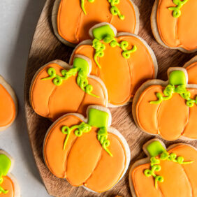 decorated pumpkin cookies with orange icing and green icing.