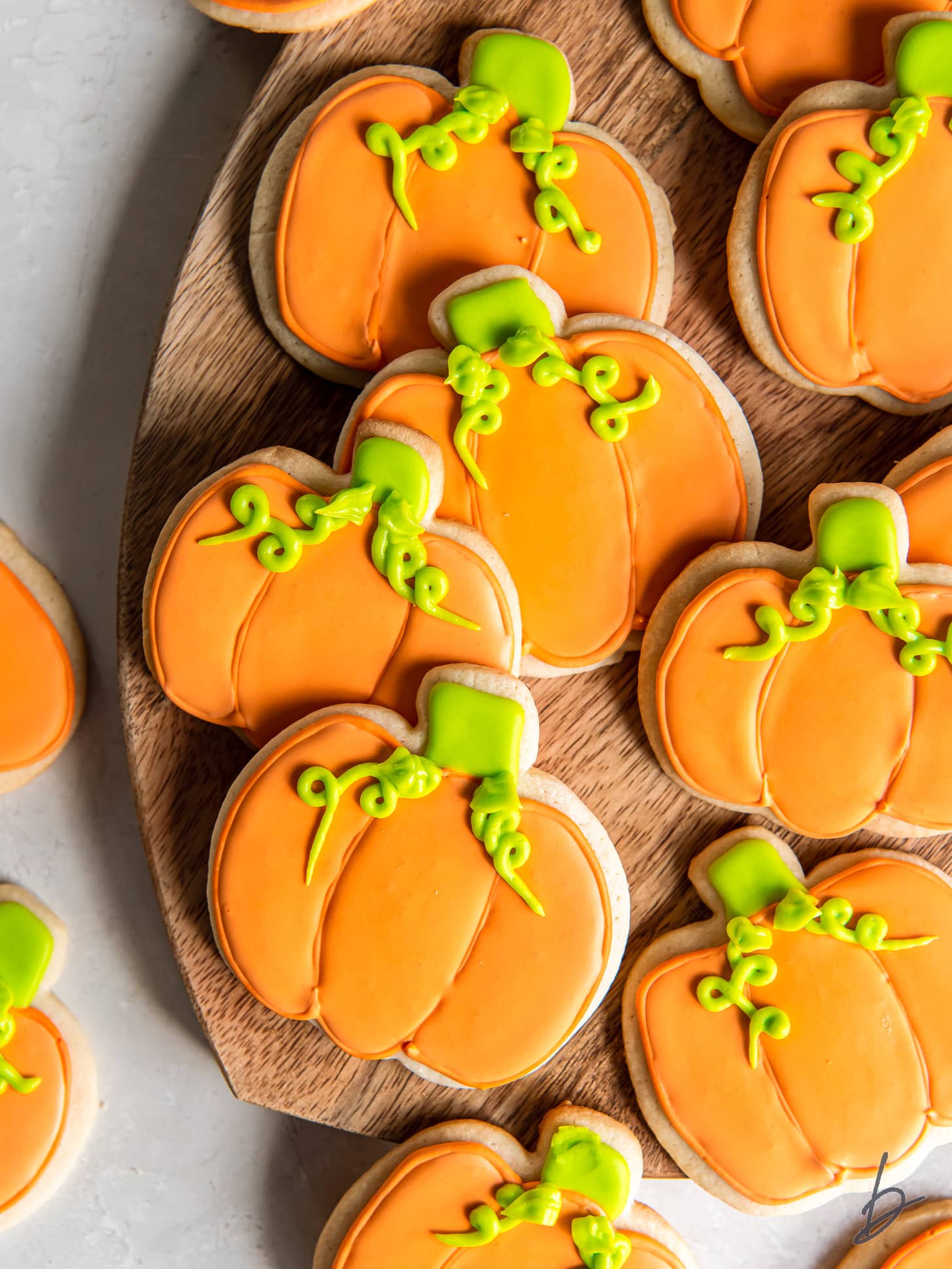 decorated pumpkin cookies with orange icing and green icing.