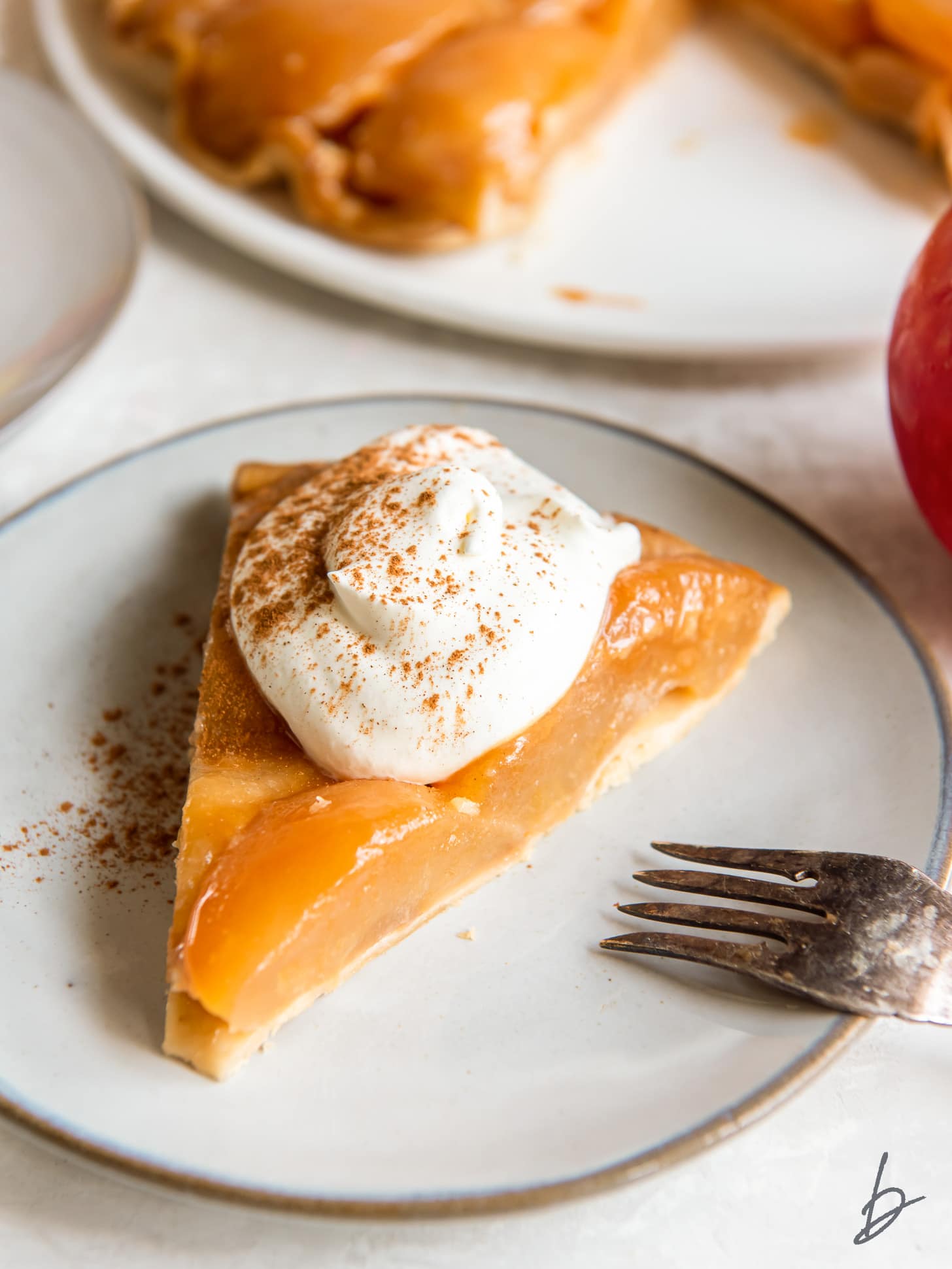 slice of apple tarte tatin on a plate with dollop of creme fraiche.