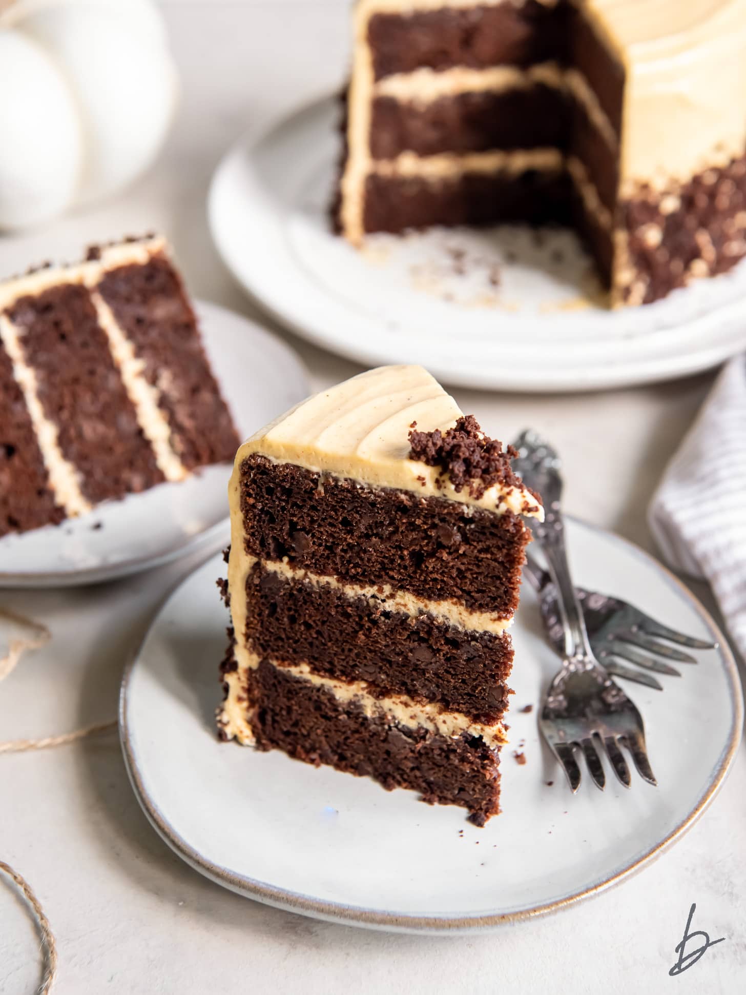 slice of layered chocolate pumpkin cake on a plate with two forks.