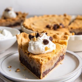 plate with slice of chocolate pecan pie with dollop of whipped cream.