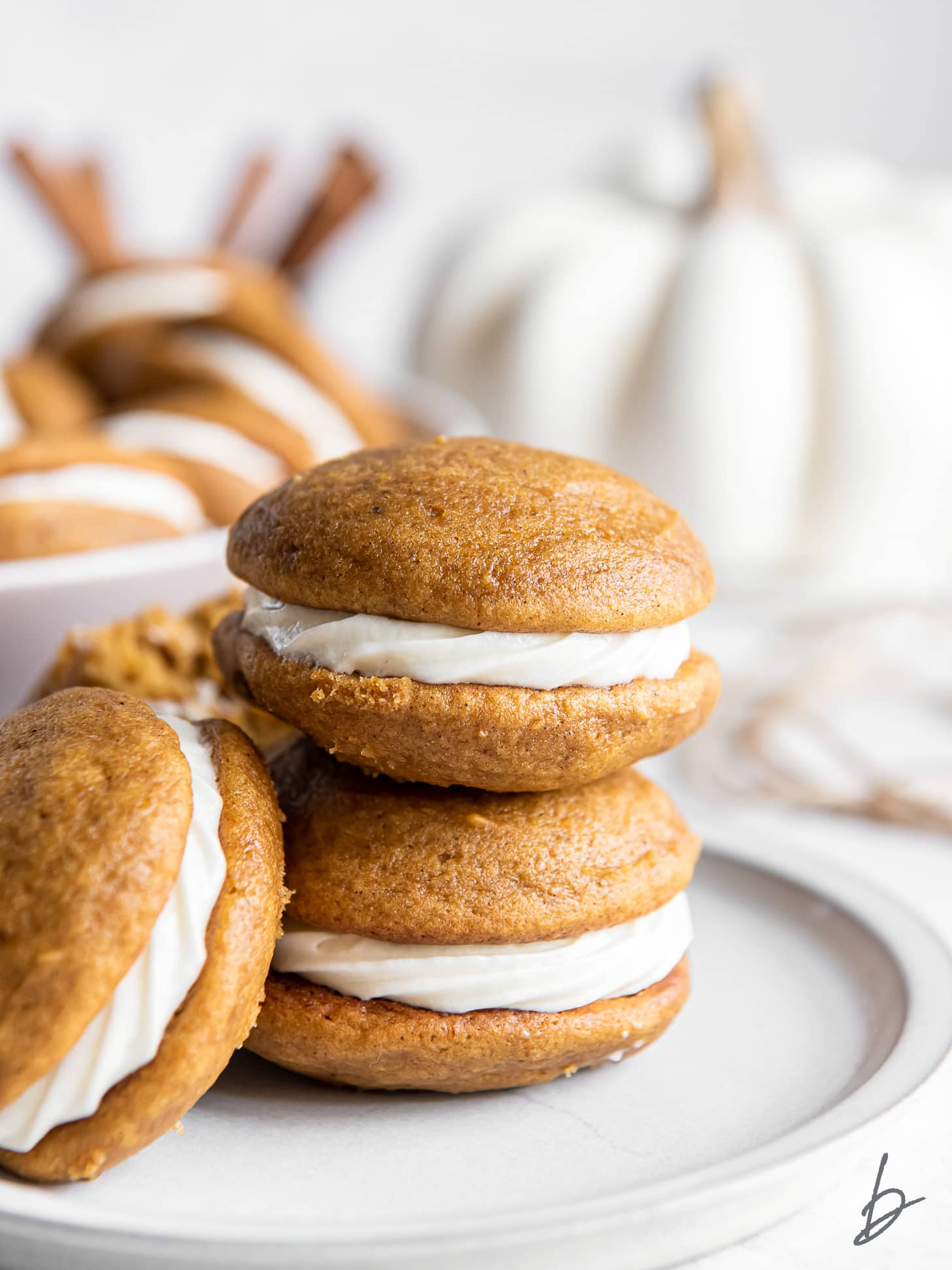 stack of two pumpkin whoopie pies with cream cheese filling.