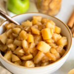 apple compote in a white bowl with a spoon.