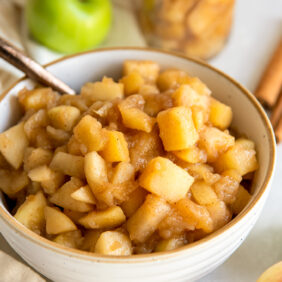 apple compote in a white bowl with a spoon.