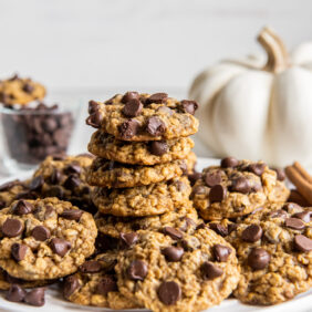 stack of pumpkin oatmeal cookies on a plate with more cookies.