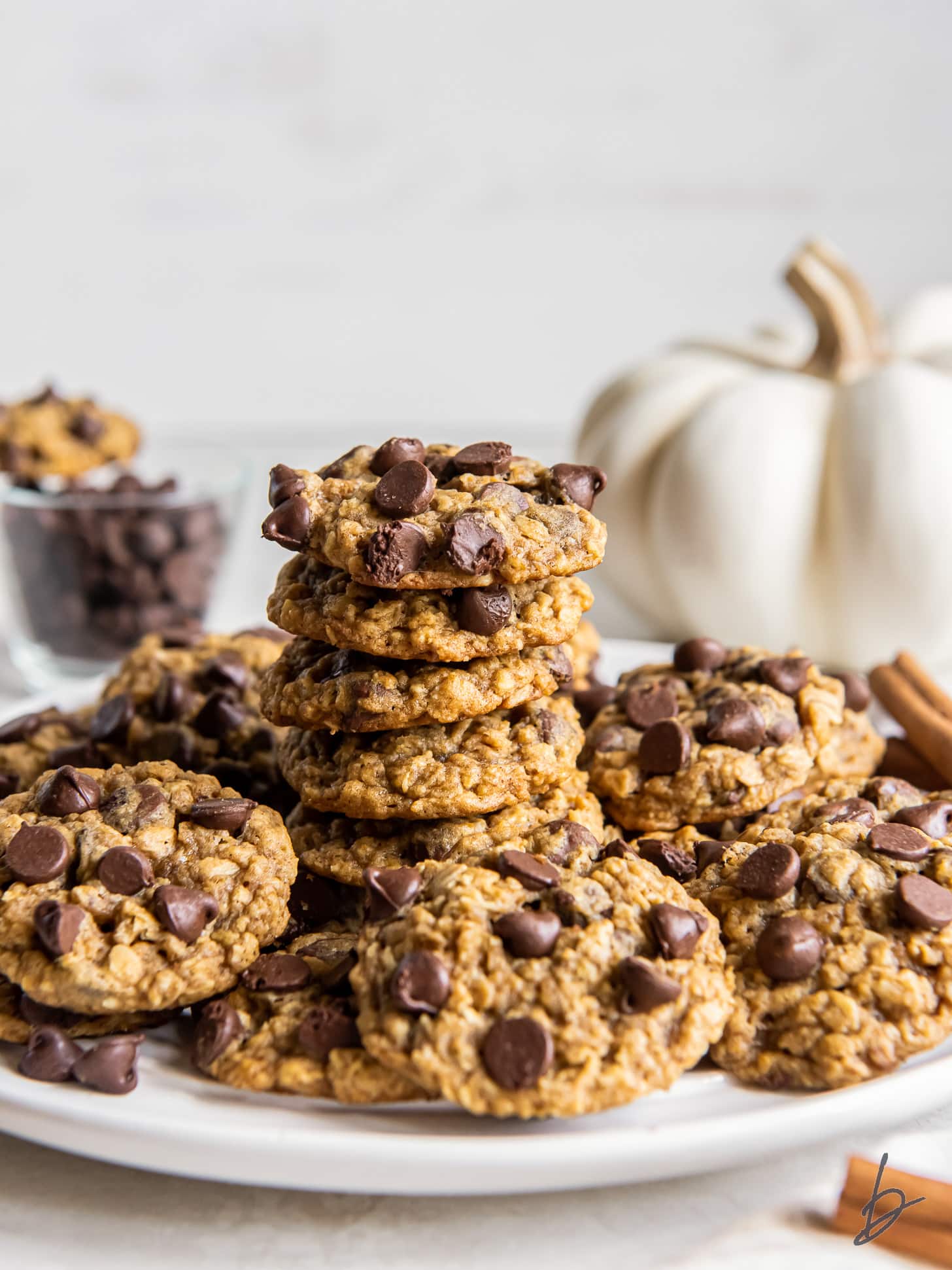 stack of pumpkin oatmeal cookies on a plate with more cookies.