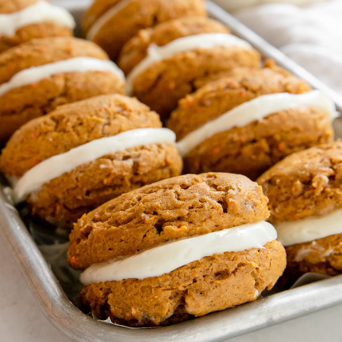 carrot pumpkin cookie sandwiches leaning against each other on a platter.