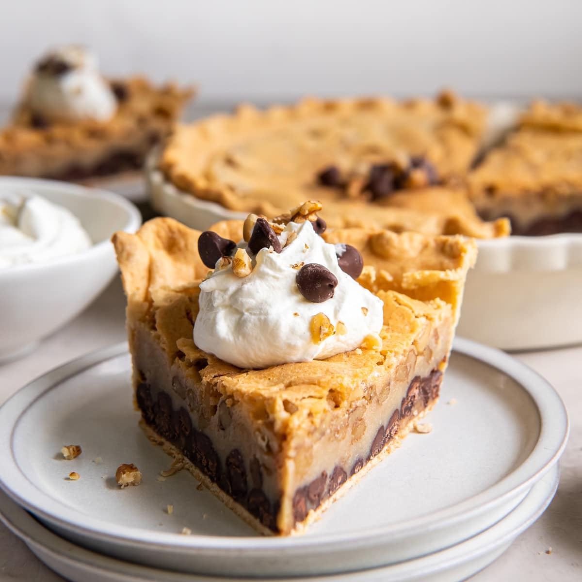 slice of chocolate walnut pie with dollop of whipped cream and chocolate chips.