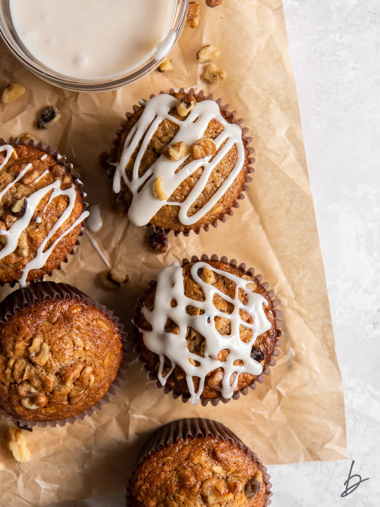 parchment paper with a few maple muffins with glaze and walnut on top.