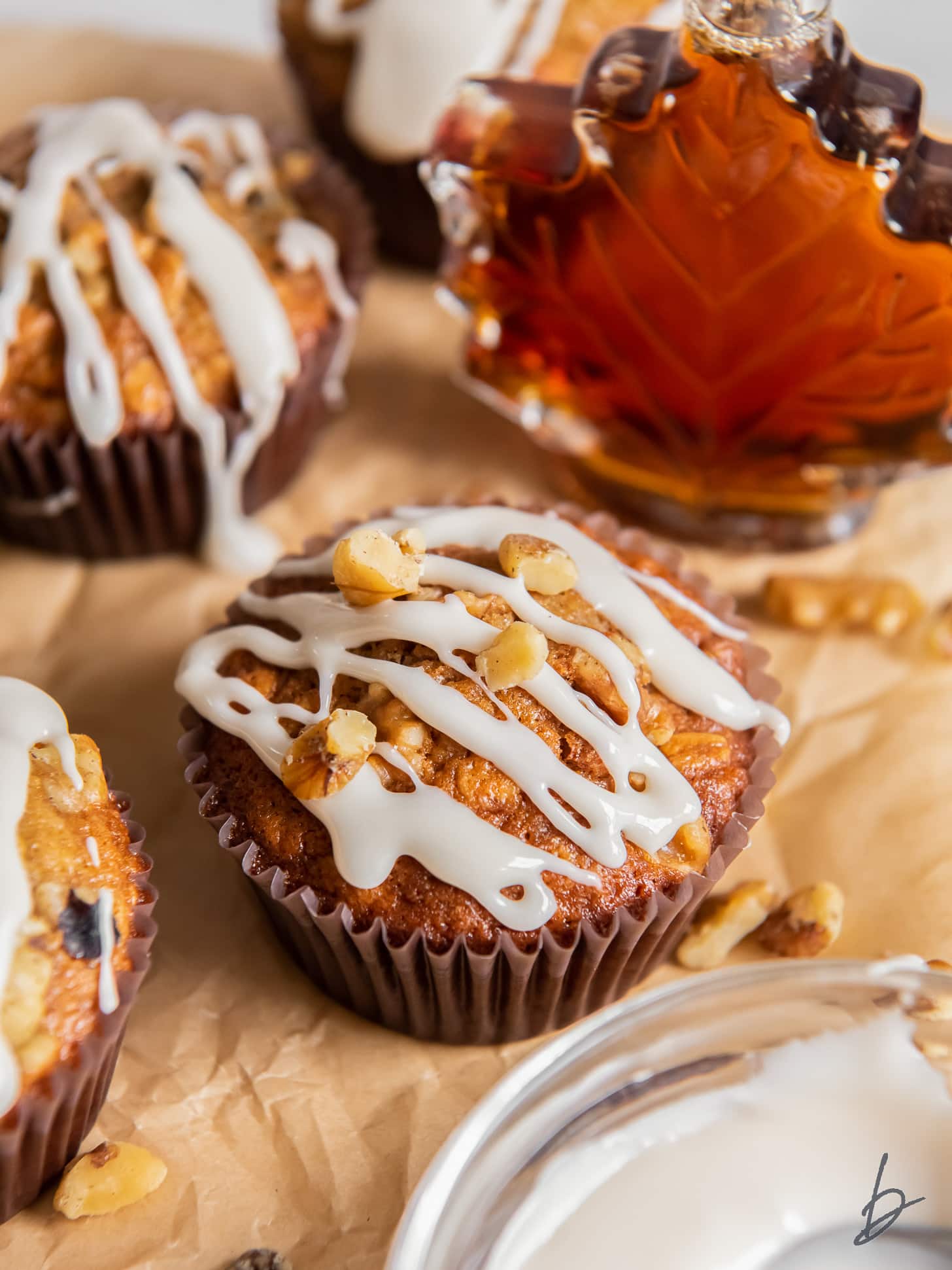 maple muffin with glaze drizzled on top with a few crushed walnuts.