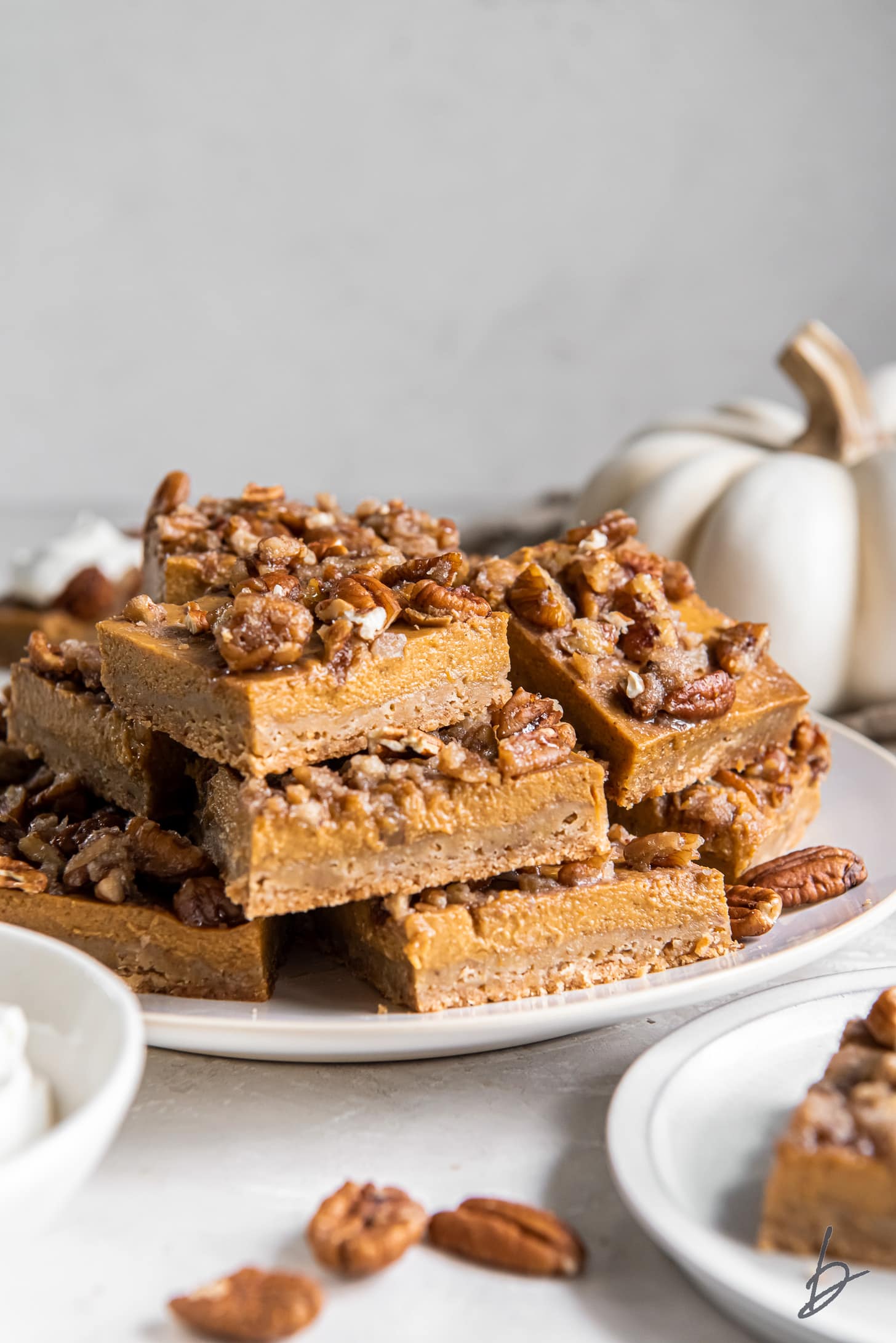 plate of pumpkin pecan pie bars stacked on top of each other.