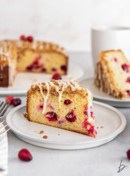 slice of cranberry cheesecake on a plate with an orange glaze dripping down sides.