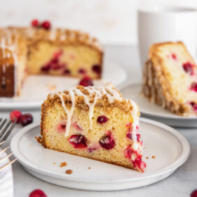 slice of cranberry cheesecake on a plate with an orange glaze dripping down sides.