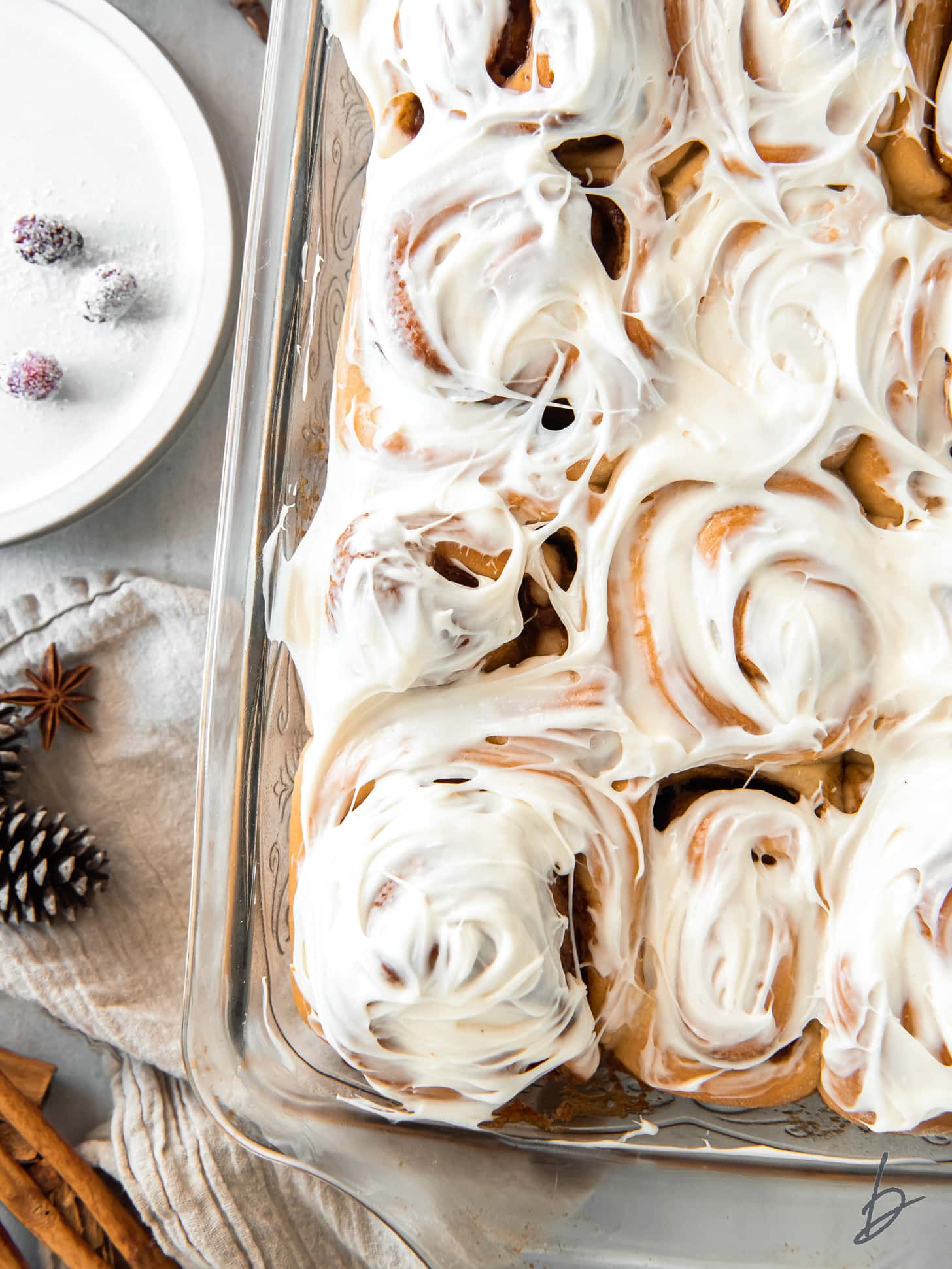 pan of gingerbread cinnamon rolls topped with cream cheese frosting.
