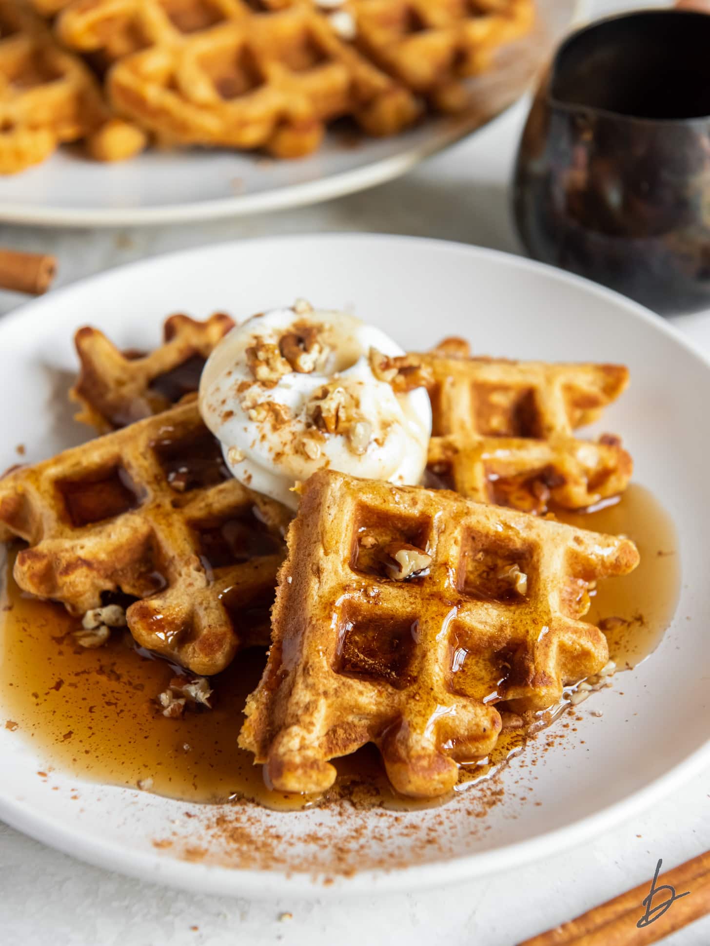 plate of sweet potato waffle triangles with maple syrup and dollop of whipped cream.