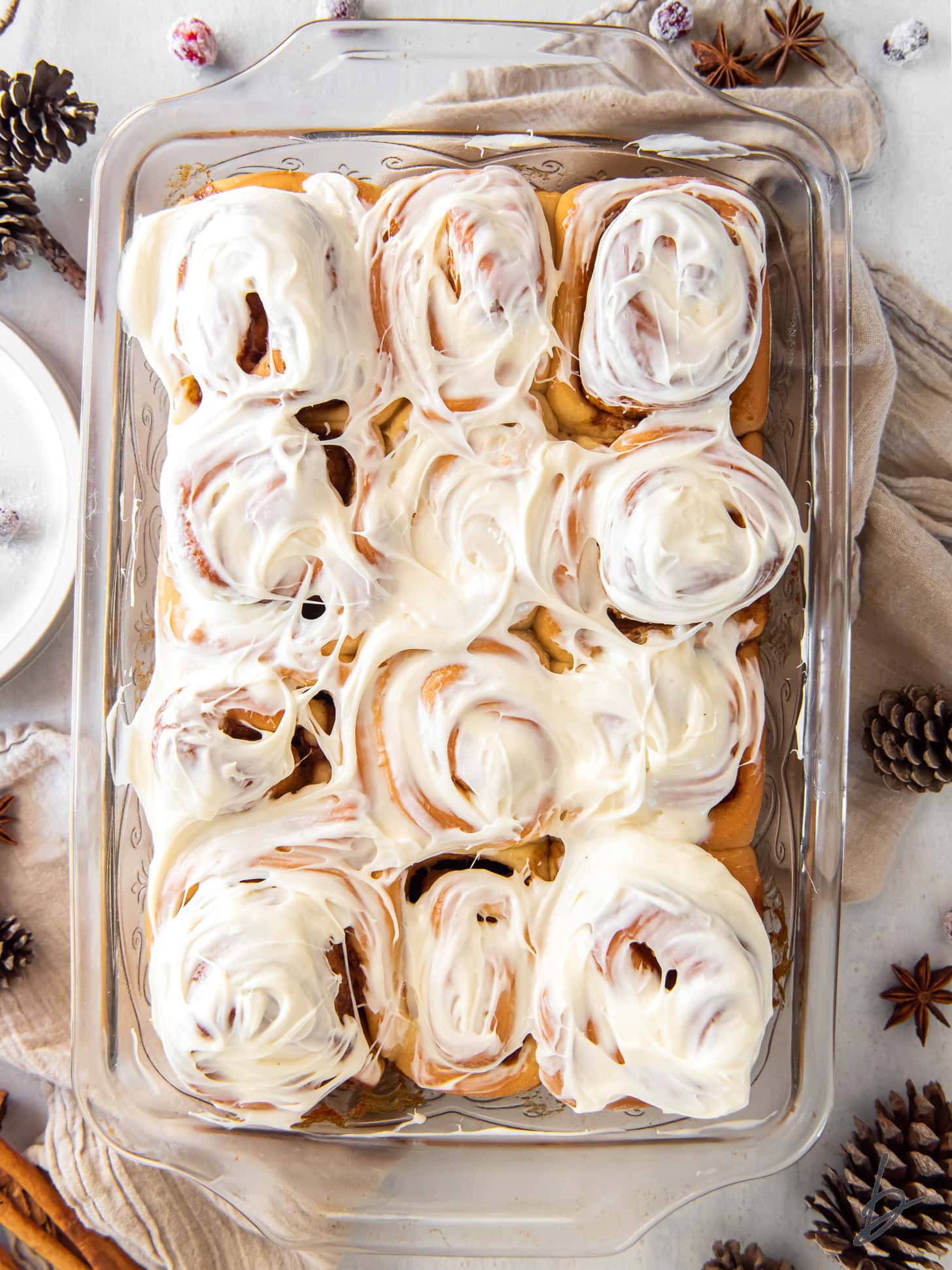 pan of gingerbread cinnamon rolls with cream cheese icing on top.