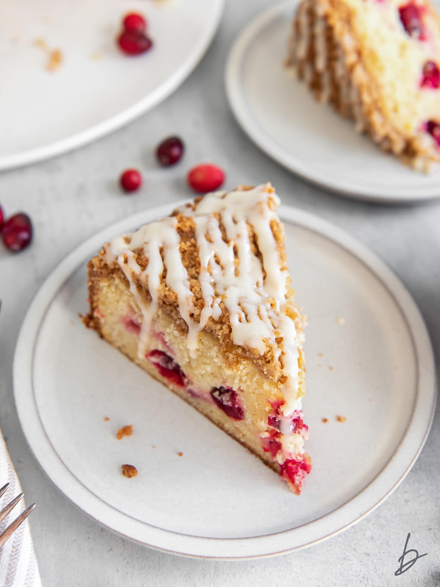 slice of cranberry coffee cake with orange icing on a plate.