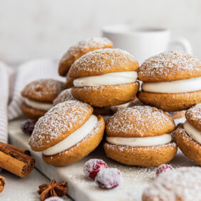 gingerbread whoopie pies filled with cream cheese frosting and stacked on top of each other.