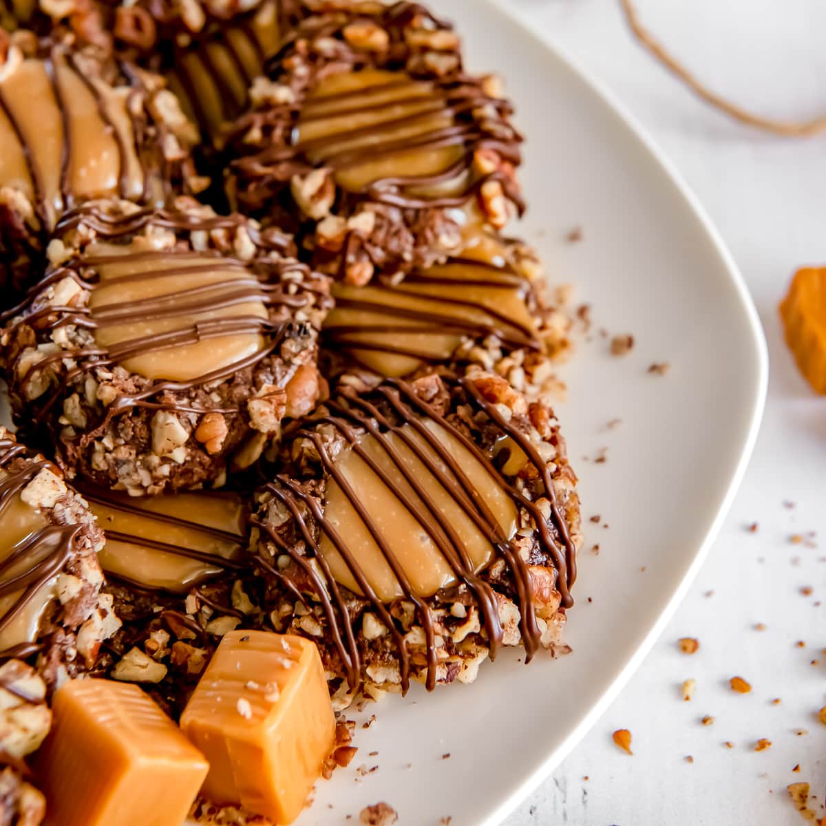 thumbprint turtle cookies with caramel and pecans on a plate.