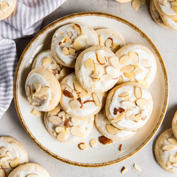 plate of iced almond cookies with sliced almonds.