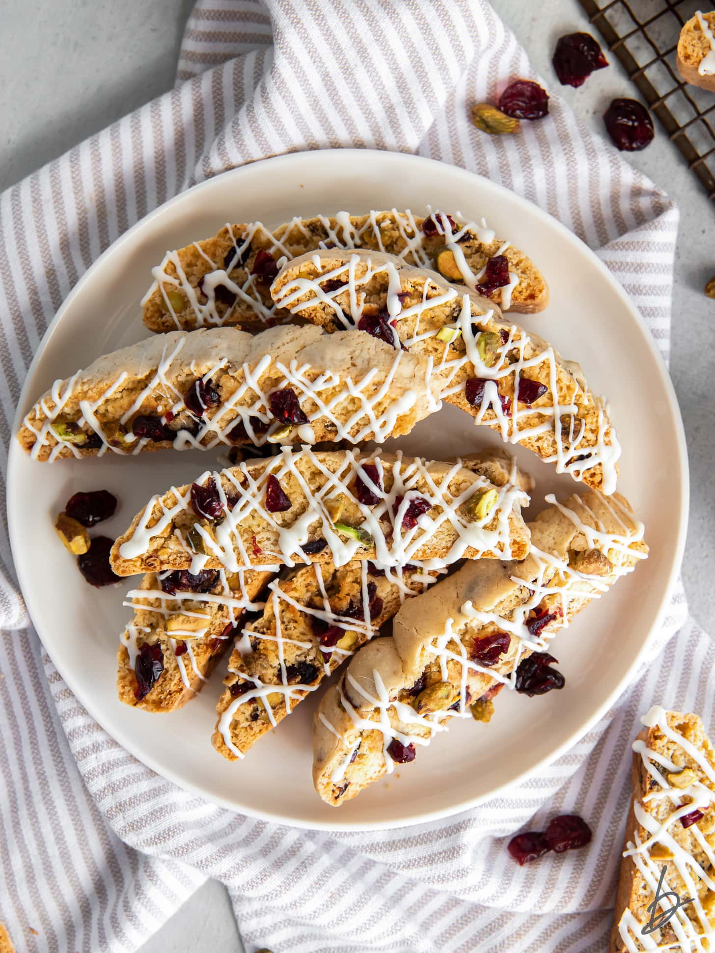 plate of cranberry pistachio biscotti drizzled with white chocolate.
