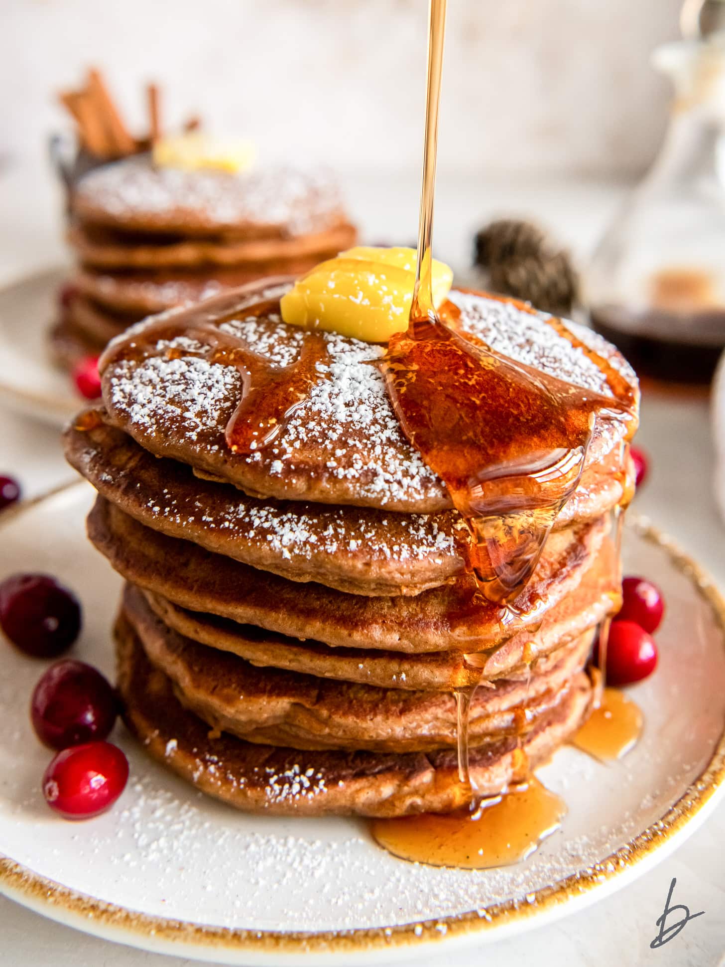 stack of gingerbread pancakes with maple syrup dripping down the sides.