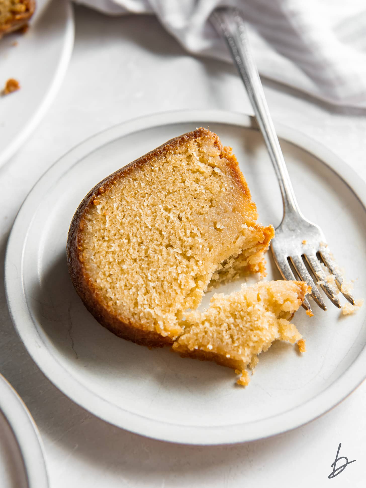 slice of rum soaked cake on a plate with fork taking a bite.