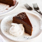 slice of sacher torte with dollop of whipped cream on a plate.