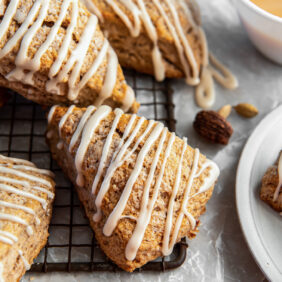 chai scone with maple glaze leaning on wire rack with more scones.