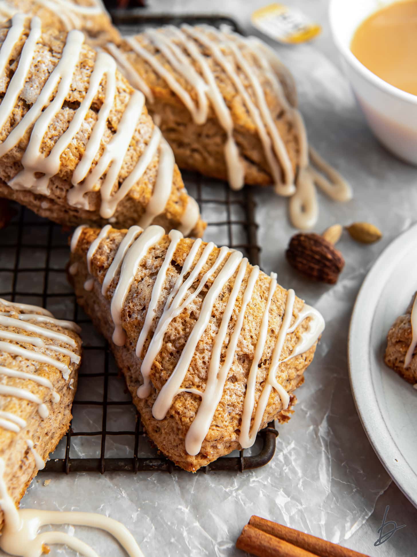 chai scone with maple glaze leaning on wire rack with more scones.