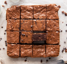 brownies cut into squares with one brownie on its side showing fudgy center.