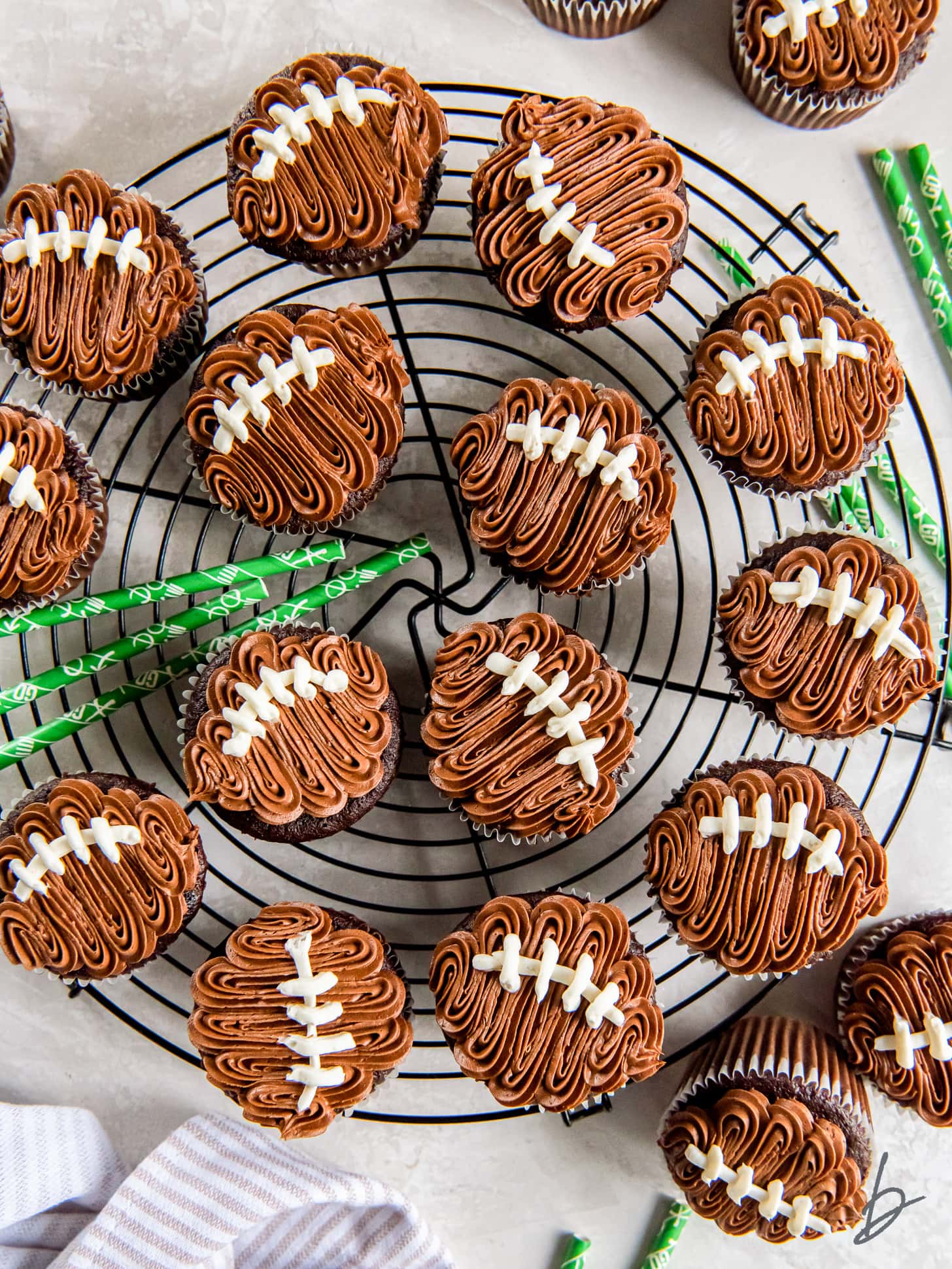 football cupcakes on a round wire rack with a few green yard line straws.