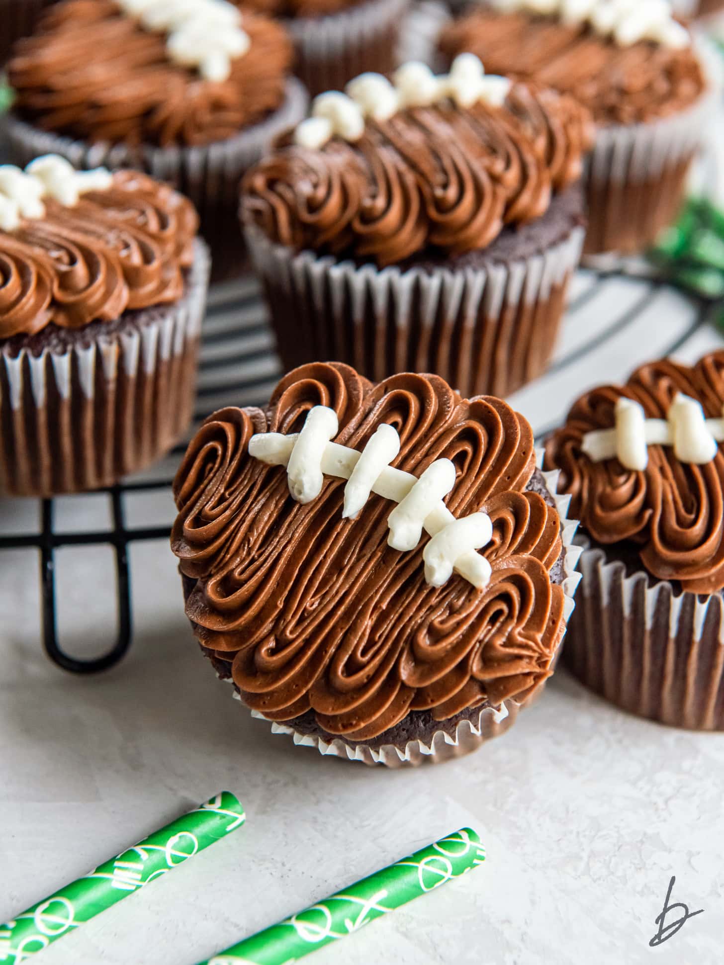 football cupcake topped with chocolate frosting and vanilla frosting stitched laces.
