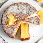 lemon olive oil cake with a few slices cut out and one on its side.