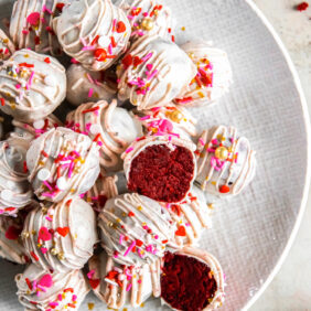 red velvet cake truffles with white chocolate and sprinkles on a plate with one ball cut in haf.